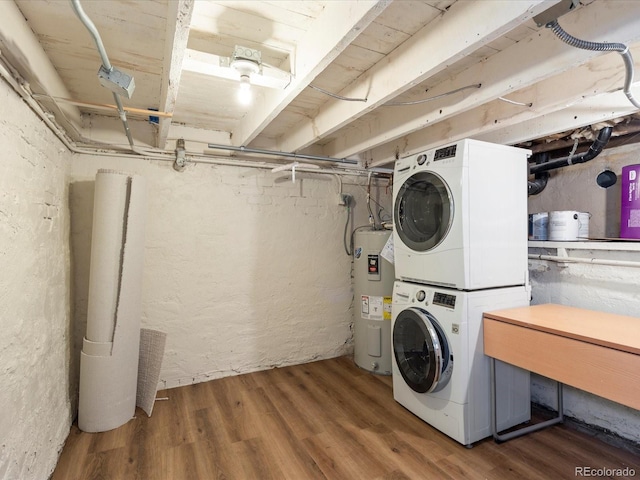 clothes washing area featuring dark hardwood / wood-style flooring, stacked washing maching and dryer, and water heater