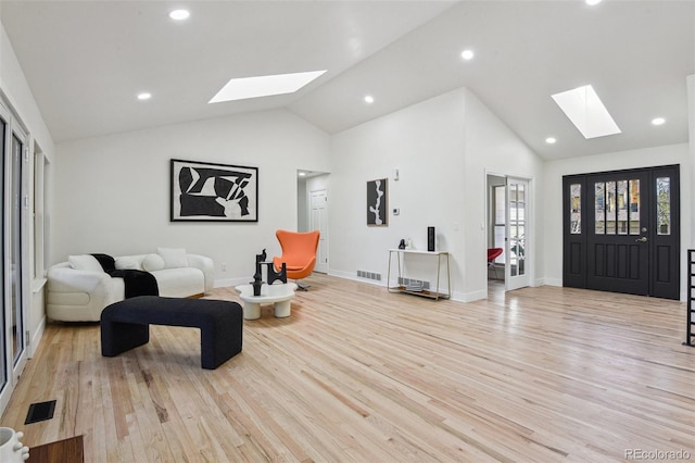 living area featuring visible vents, light wood-type flooring, and a skylight