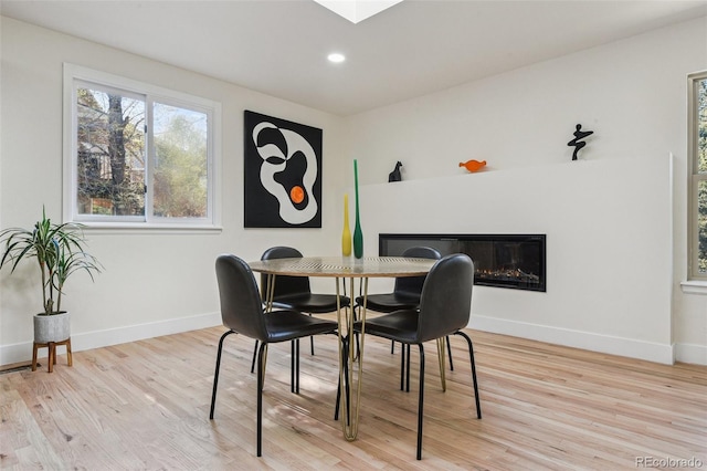 dining room with a glass covered fireplace, baseboards, and wood finished floors