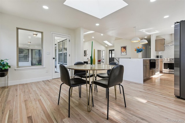 dining room featuring light wood-style flooring, vaulted ceiling with skylight, baseboards, and recessed lighting
