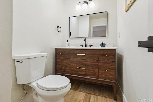 bathroom featuring toilet, vanity, and wood finished floors