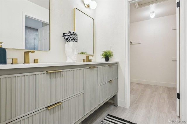 full bathroom featuring baseboards and double vanity