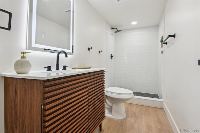 bathroom featuring tiled shower, vanity, toilet, and wood finished floors