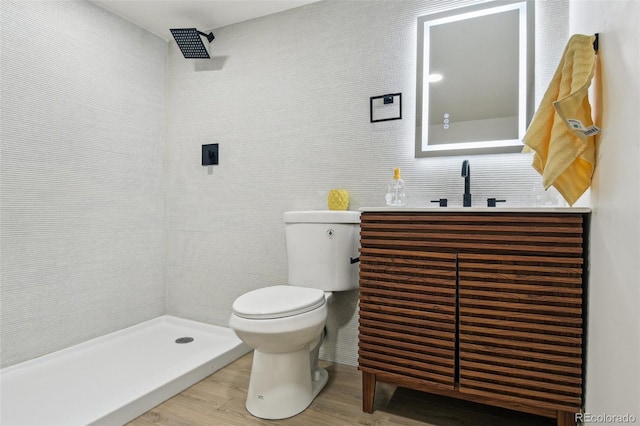 bathroom featuring vanity, toilet, tile walls, a tile shower, and wood finished floors