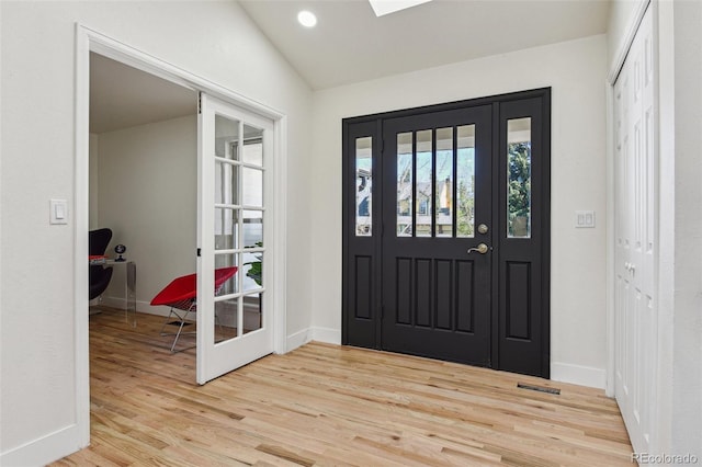 foyer with light wood-style flooring, visible vents, baseboards, and lofted ceiling