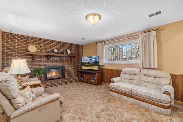 living room featuring a fireplace, light carpet, a textured ceiling, and wood walls