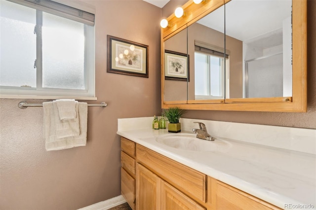 bathroom with a healthy amount of sunlight, a shower with shower door, and vanity