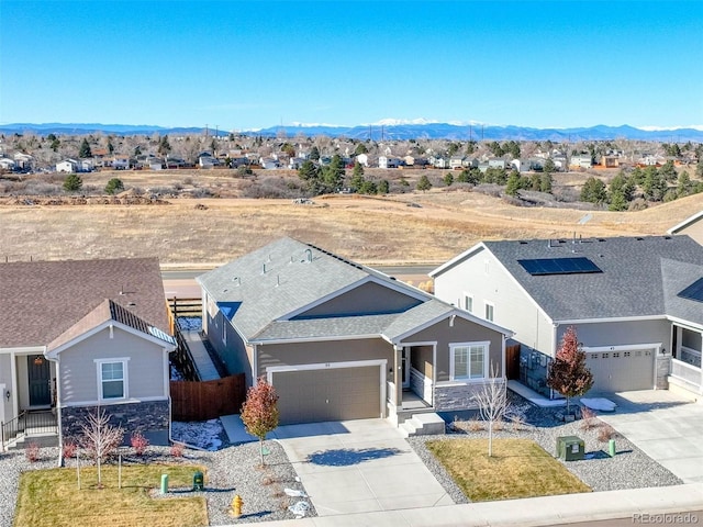 55 S Edge Cliff St, Castle Rock, CO 80104 - view of front of house featuring concrete driveway, stone siding, a mountain view, and roof with shingles