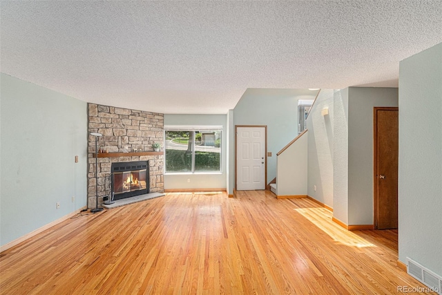 8753 W Cornell Ave Unit 12-1, Denver, CO 80227 - unfurnished living room featuring a textured ceiling, wood finished floors, a stone fireplace, and stairs