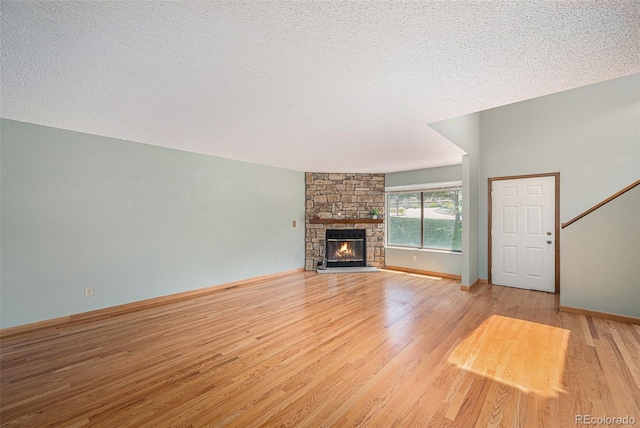 8753 W Cornell Ave Unit 12-1, Denver, CO 80227 - unfurnished living room featuring light wood-style flooring, a stone fireplace, and a textured ceiling