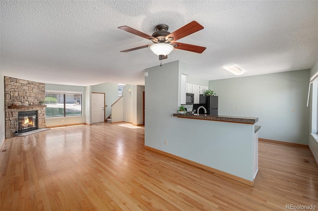 8753 W Cornell Ave Unit 12-1, Denver, CO 80227 - unfurnished living room featuring a ceiling fan, light wood-style flooring, a textured ceiling, stairway, and a fireplace