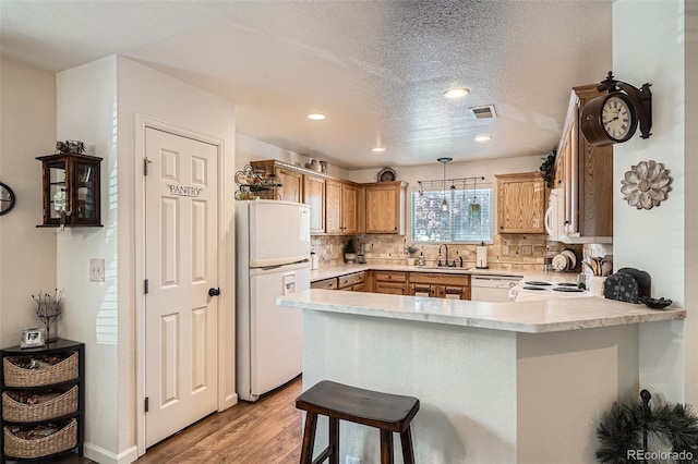 5843 Ceylon St, Denver, CO 80249 - kitchen with white appliances, a peninsula, light wood-style floors, light countertops, and tasteful backsplash