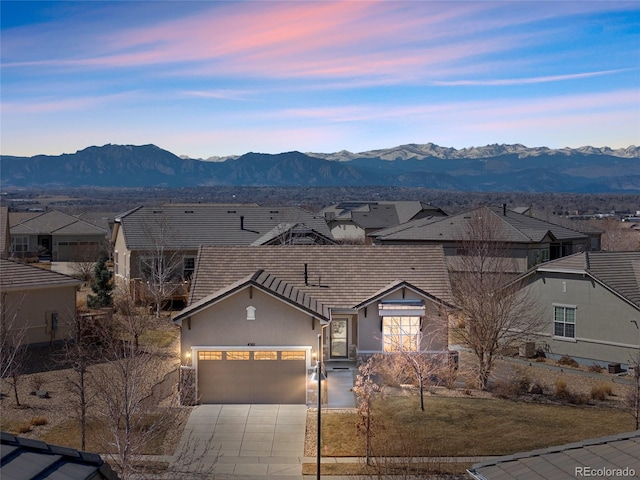 view of front of home featuring driveway, a mountain view, an attached garage, stucco siding, and a residential view