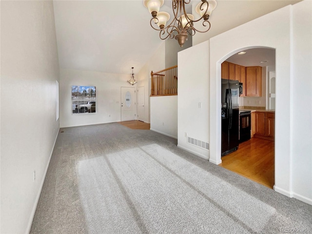 unfurnished living room with a chandelier, light colored carpet, and high vaulted ceiling