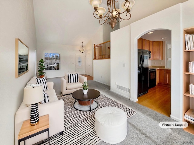 living room featuring an inviting chandelier, high vaulted ceiling, and light colored carpet