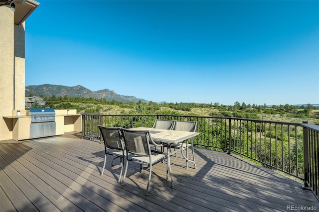 wooden deck featuring a mountain view, grilling area, and exterior kitchen