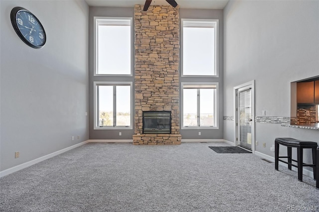 unfurnished living room with ceiling fan, carpet, and a high ceiling