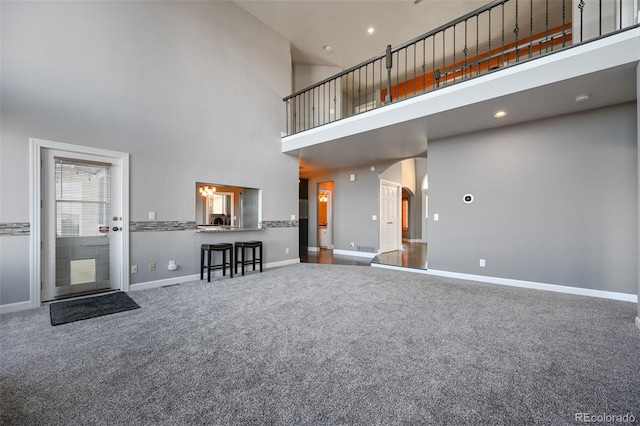 unfurnished living room featuring carpet floors and a high ceiling