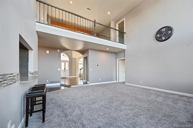 carpeted living room featuring a towering ceiling