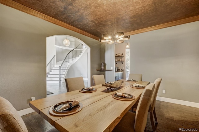 dining room with dark wood-type flooring, an inviting chandelier, and ornamental molding