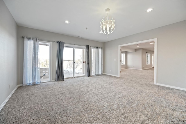 spare room with light colored carpet and an inviting chandelier