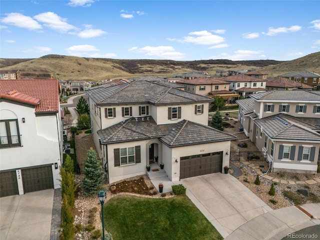 view of front of property featuring a tile roof, driveway, a mountain view, and a residential view