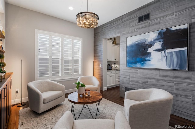 living area with tile walls, baseboards, an accent wall, and a notable chandelier
