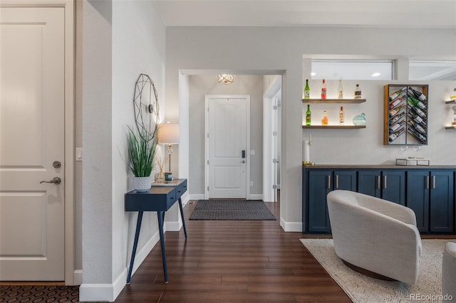 foyer entrance featuring indoor bar, baseboards, and dark wood-style floors