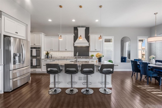 kitchen featuring stainless steel appliances, dark wood-style floors, tasteful backsplash, white cabinetry, and premium range hood