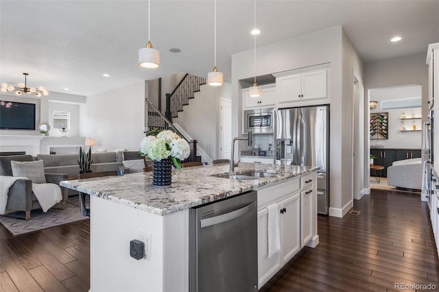 kitchen with white cabinets, a sink, dark wood-style flooring, open floor plan, and appliances with stainless steel finishes