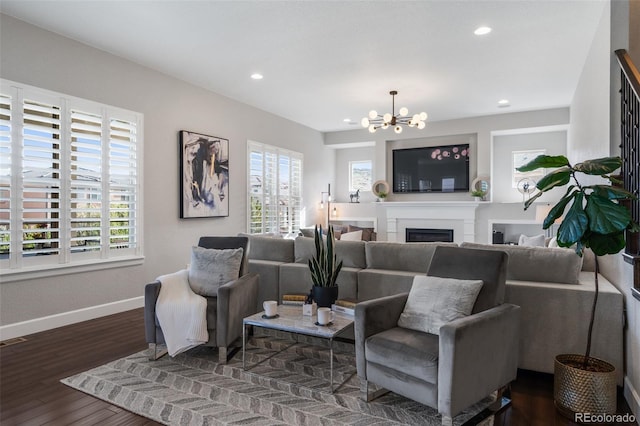 living area featuring plenty of natural light, baseboards, an inviting chandelier, and dark wood-type flooring