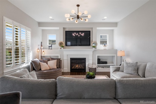 living room featuring wood finished floors, a glass covered fireplace, an inviting chandelier, and recessed lighting