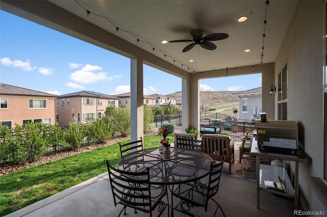 view of patio / terrace featuring fence, outdoor dining space, a ceiling fan, and a residential view