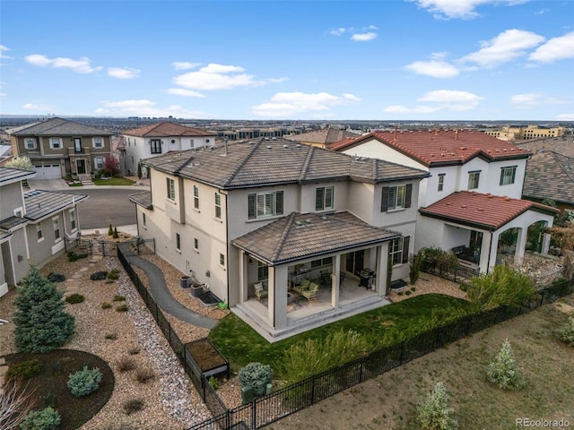 rear view of property featuring a residential view, a fenced backyard, a tiled roof, central AC, and stucco siding