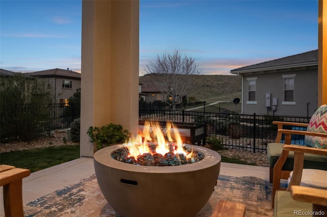 patio terrace at dusk featuring a fire pit and fence