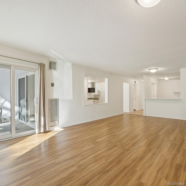 2880 S Locust St Unit 109S, Denver, CO 80222 - unfurnished living room featuring a textured ceiling, light wood-style floors, and baseboards