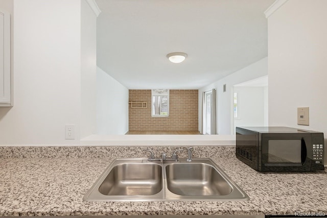 2880 S Locust St Unit 109S, Denver, CO 80222 - kitchen view of black microwave, a sink, white cabinetry, and backsplash