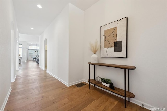 hallway with arched walkways, recessed lighting, visible vents, light wood-style flooring, and baseboards