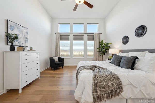 bedroom with lofted ceiling, light wood finished floors, baseboards, and a ceiling fan