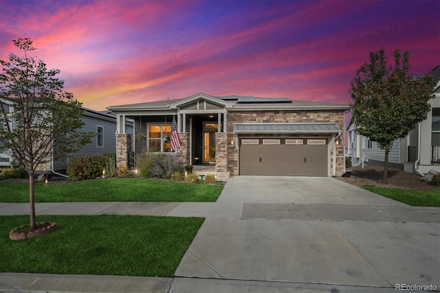 view of front of home featuring stone siding, a lawn, solar panels, and concrete driveway