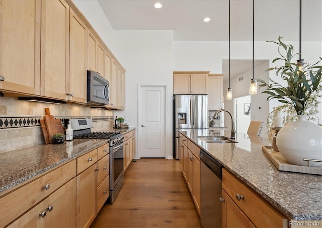 kitchen with decorative backsplash, stainless steel appliances, light wood-type flooring, light brown cabinets, and a sink