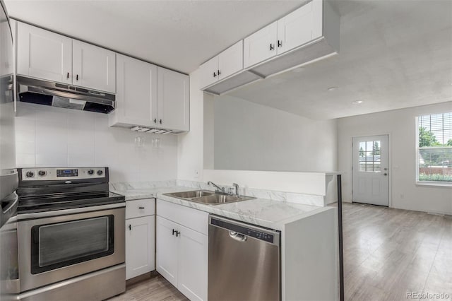 3281 S Estes St, Lakewood, CO 80227 - kitchen with stainless steel appliances, under cabinet range hood, light wood-style flooring, white cabinetry, and a peninsula