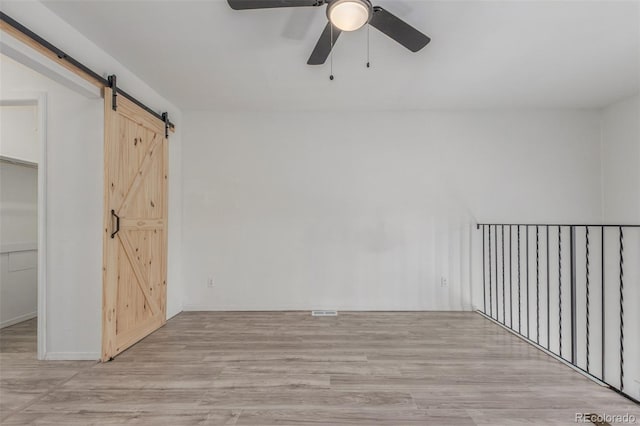 3281 S Estes St, Lakewood, CO 80227 - unfurnished bedroom featuring a barn door, light wood finished floors, and ceiling fan
