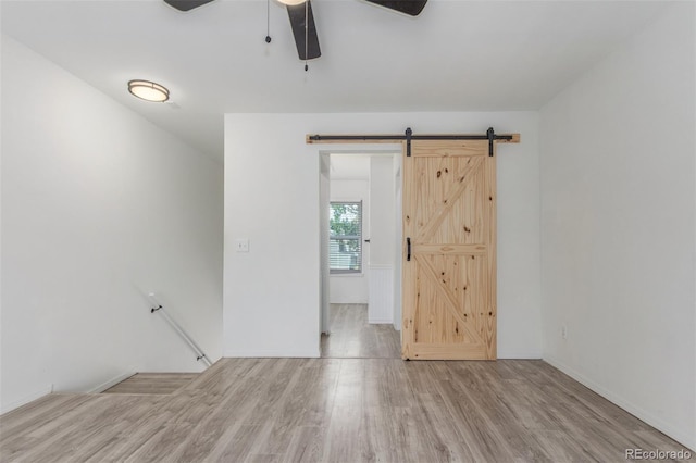 3281 S Estes St, Lakewood, CO 80227 - empty room with a barn door, ceiling fan, and wood finished floors
