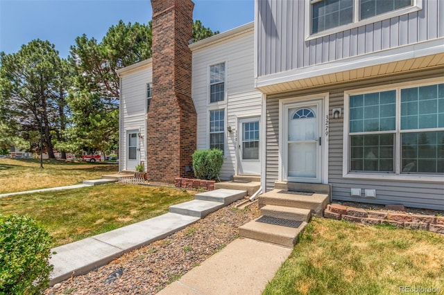 3281 S Estes St, Lakewood, CO 80227 - view of front of house with board and batten siding, a front yard, and a chimney