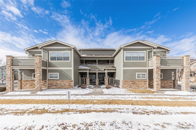 view of front of home with stone siding, cooling unit, and a balcony