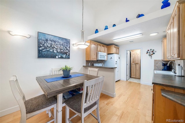 dining space featuring light wood-type flooring and baseboards