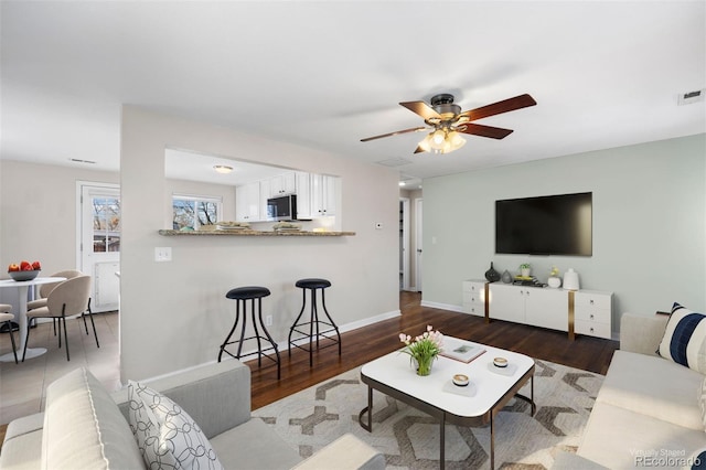 living room featuring ceiling fan and dark hardwood / wood-style floors