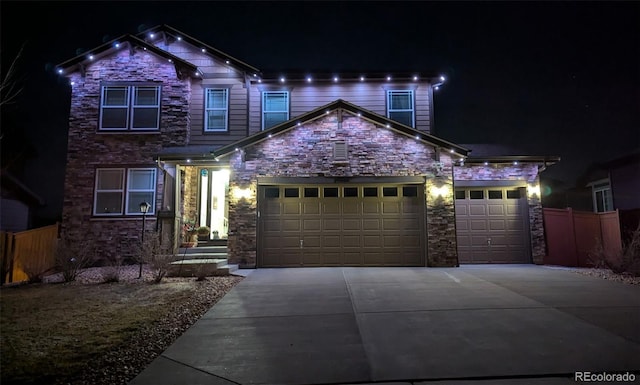 view of front of house with concrete driveway, an attached garage, fence, and stone siding