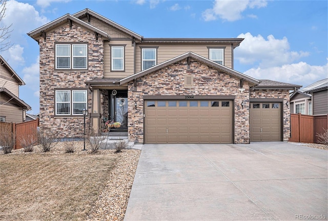 craftsman inspired home with an attached garage, concrete driveway, and fence